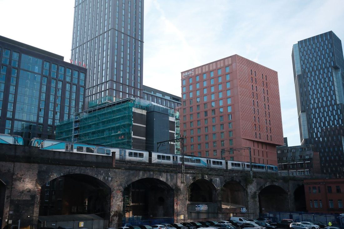 A train travels through a modern cityscape featuring high-rise buildings and urban infrastructure.