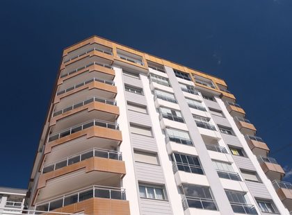 A modern residential building with balconies in İzmir, Türkiye under a clear blue sky.