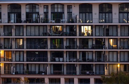 Facade of a modern apartment building at twilight with some rooms illuminated, creating a contrast with the exterior.