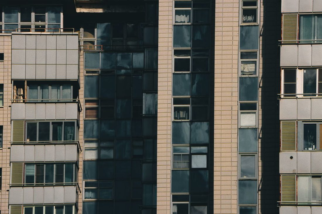 Close-up view of a modern apartment building with diverse window designs and tiled facade in an urban setting.