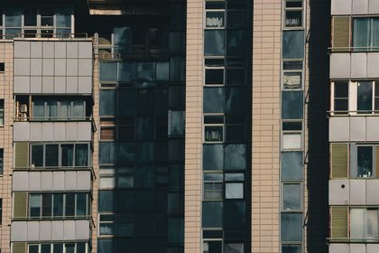 Close-up view of a modern apartment building with diverse window designs and tiled facade in an urban setting.