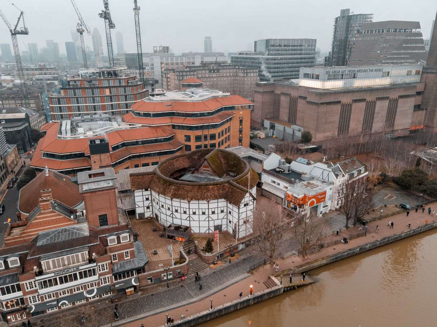A stunning aerial shot of London's Globe Theatre along the riverbanks with surrounding modern architecture.