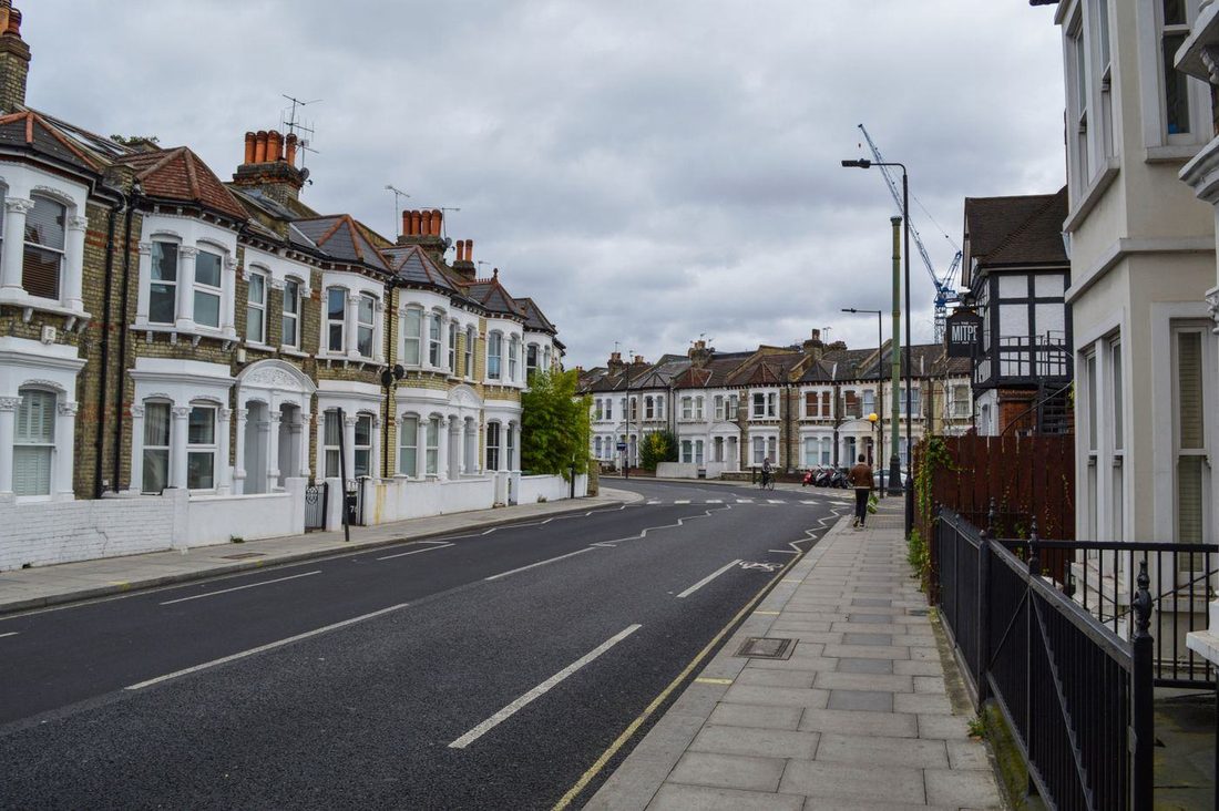 Exterior of contemporary solid houses and concrete road with pavement under cloudy nasty sky