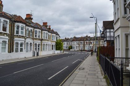 Exterior of contemporary solid houses and concrete road with pavement under cloudy nasty sky