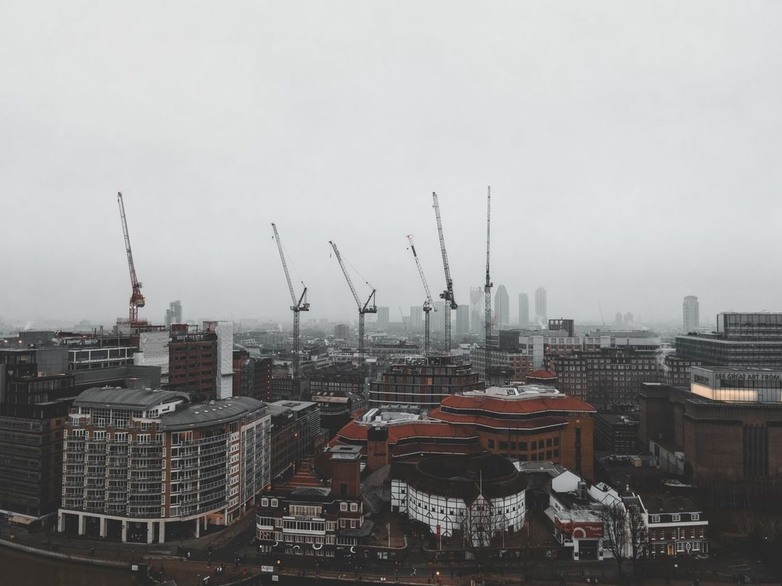 Foggy day in London featuring construction cranes over the cityscape in a moody atmosphere.