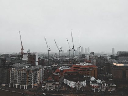 Foggy day in London featuring construction cranes over the cityscape in a moody atmosphere.