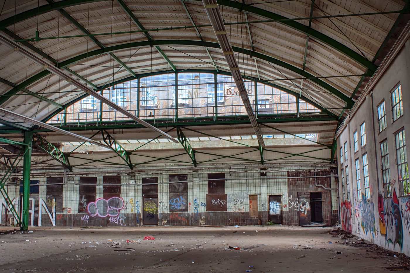 Interior of an abandoned warehouse with graffiti and debris, showcasing urban decay.