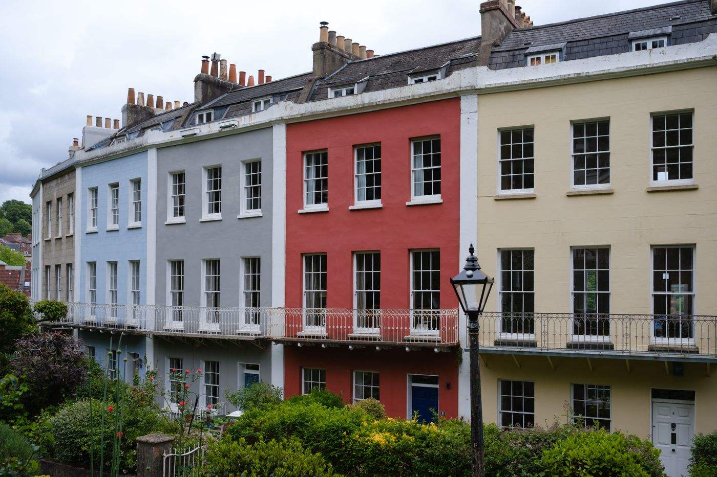 A row of colorful Georgian terraced houses in a quaint suburban neighborhood.