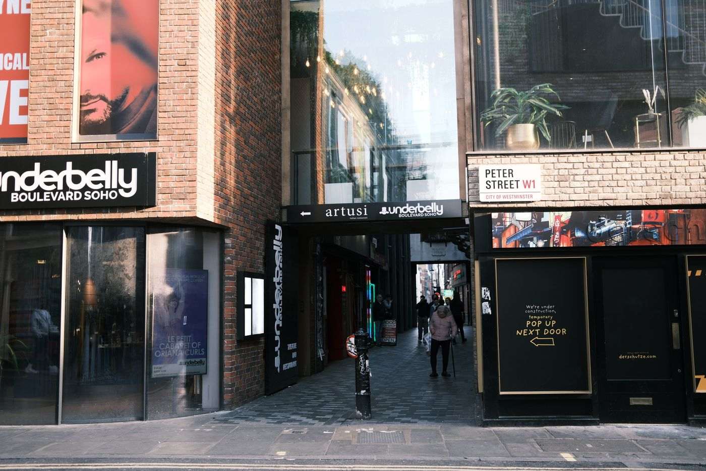View of Underbelly Boulevard Soho entrance on Peter Street, London with pedestrians.