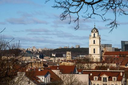 A beautiful view of Vilnius city featuring historic architecture and a prominent church tower under a clear sky.