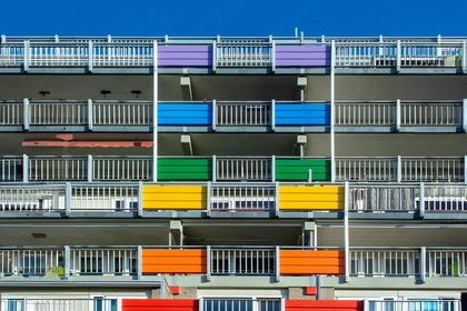 Vibrant apartment building with multi-colored balconies under a clear blue sky.