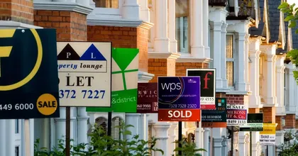 Row of houses with for sale signs.