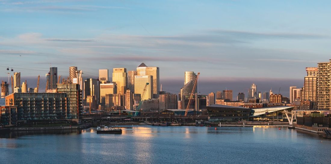 Captivating sunrise view of London's Royal Docks with towering skyscrapers reflecting in calm waters.