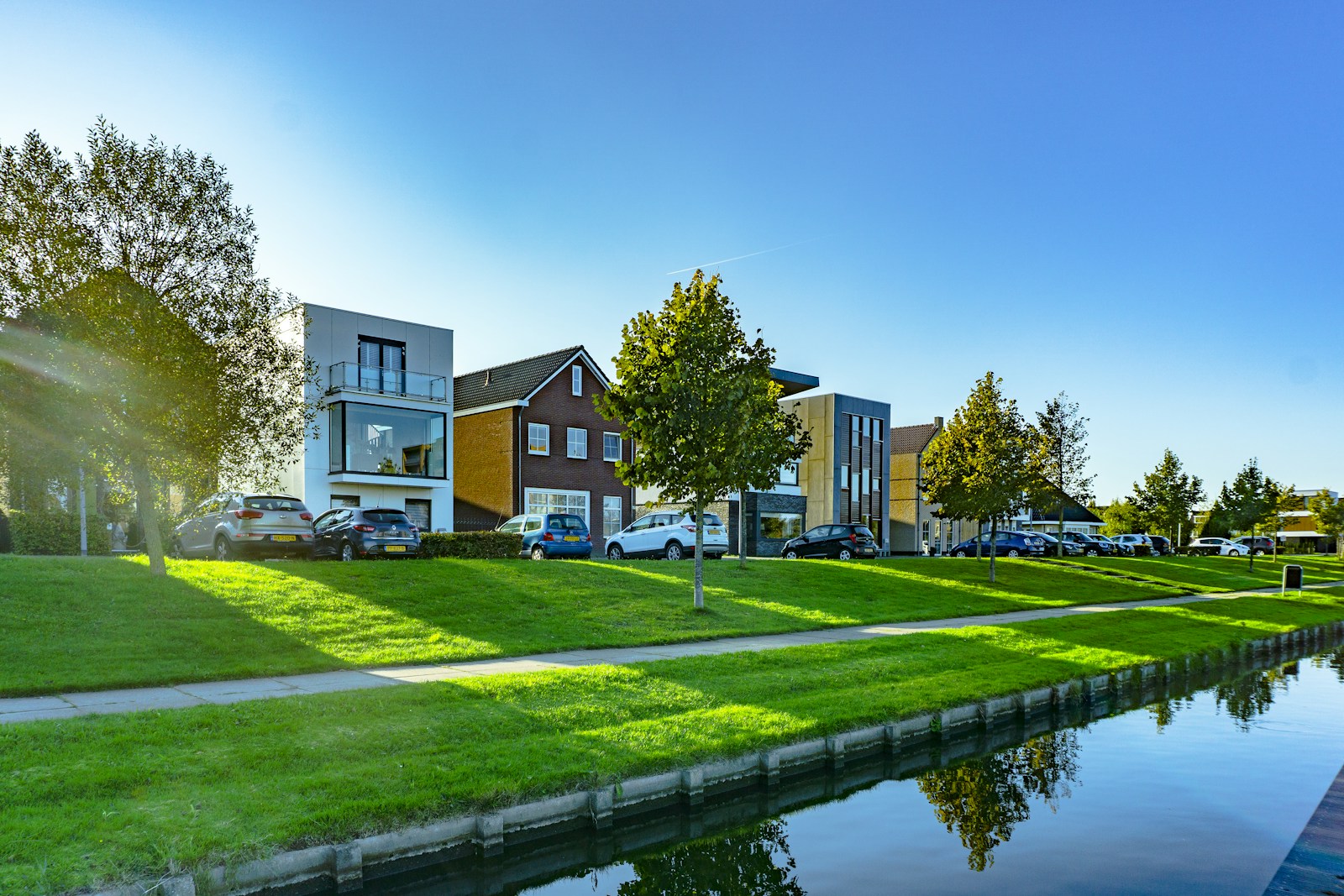 white and brown house near green grass field and body of water during daytime