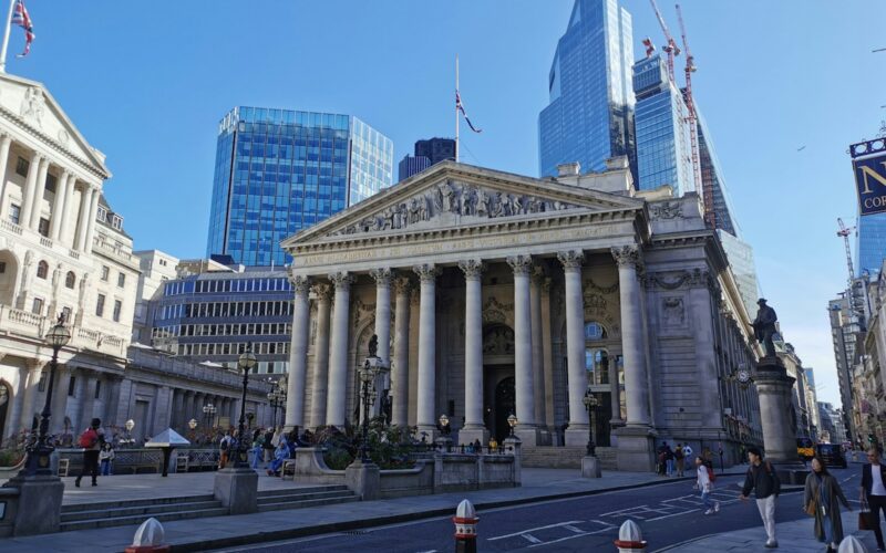 a large building with columns and a statue in front of it with Royal Exchange, London in the background