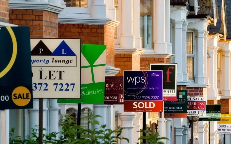 Row of houses with for sale signs.