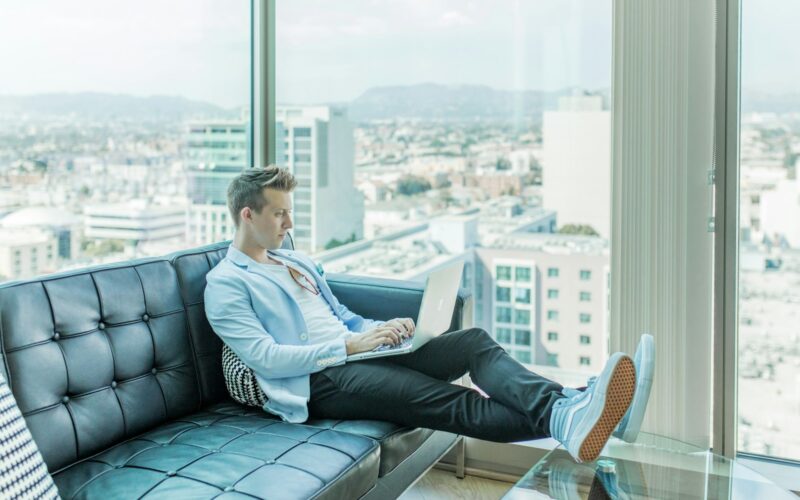 man sitting on sofa while using laptop